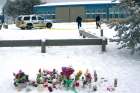 A makeshift memorial is seen Jan. 25 near a Royal Canadian Mounted Police vehicle parked outside La Loche Community School in La Loche, Sask. Police charged a 17-year-old young man with four counts of first-degree murder and seven counts of attempted murder in the Jan. 22 mass shooting at the school and a nearby home.