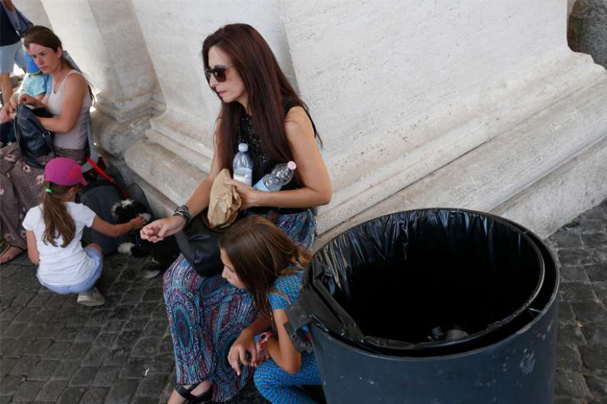 A woman holds water bottles next to a trash can under the St. Peter&#039;s Square colonnade at the Vatican July 16, 2019. A Vatican official said the Vatican is collecting 22 pounds of plastic a day from trash containers under the colonnade.