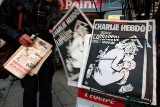 A man takes a copy of the latest edition of the French weekly Charlie Hebdo with the title “One year on, The assassin still on the run” displayed at a kiosk in Nice, France, on Jan. 6, 2016. France this week commemorates the victims of last year’s Islamist militant attacks on the satirical publication and a Jewish supermarket with eulogies, memorial plaques and another cartoon lampooning religion. 