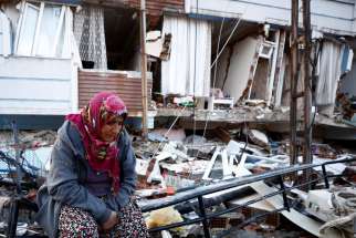 An earthquake survivor sits amid the rubble of destroyed homes in Hatay, Turkey, Feb.7, 2023. A powerful 7.8 magnitude earthquake rocked areas of Turkey and Syria early Feb. 6, toppling hundreds of buildings and killing thousands.