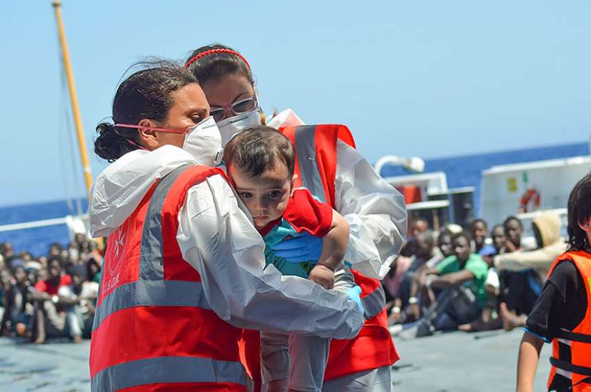 Volunteers of the Order of Malta&#039;s Italian Relief Corps provide assistant to an infant rescued in the Mediterranean Sea. Since 2007, the order&#039;s relief corps has worked alongside the Italian coast guard rescuing refugees stranded in the Mediterranean Sea.