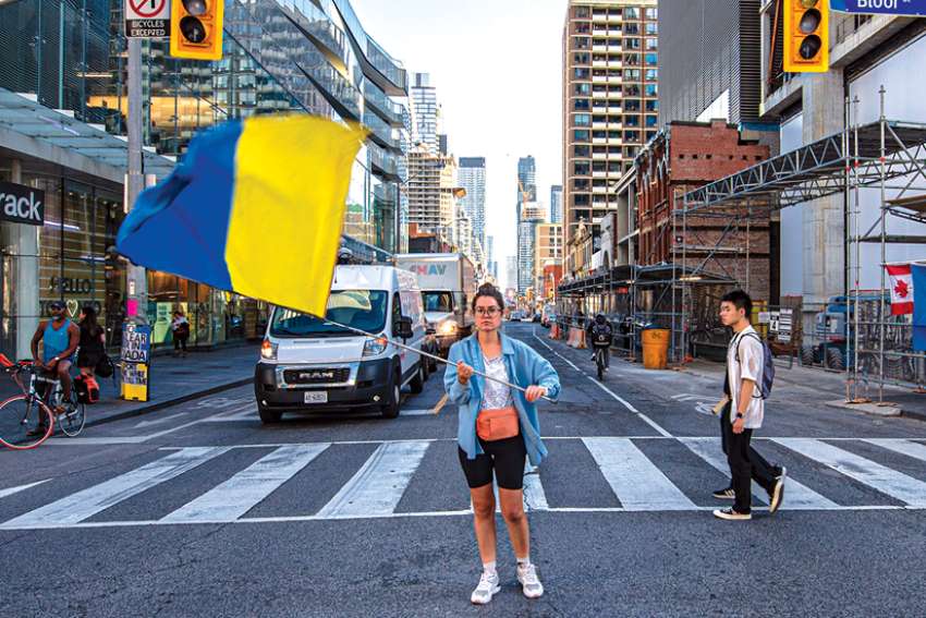 Olena Kycha, a Ukrainian refugee in Toronto, waves the Ukraine flag amid rush hour traffic at Yonge and Bloor Streets in downtown Toronto.