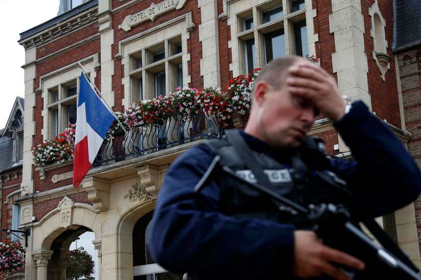 A policeman reacts as he secures a position in front of city hall after two assailants killed 84-year-old Father Jacques Hamel and took five people hostage during a weekday morning Mass at the church in Saint-Etienne-du-Rouvray, France, near Rouen July 26.