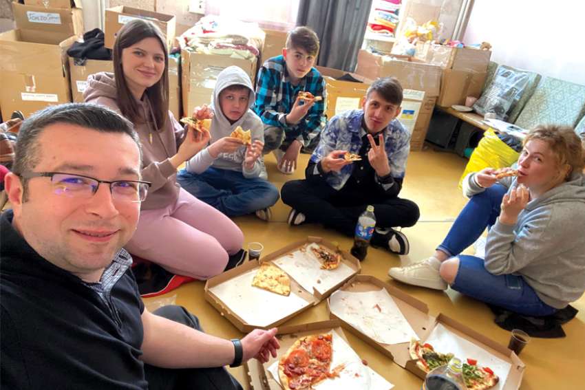 Fr. Jacob enjoying pizza with kids at Parish of All Saints Church, a temporary shelter for Ukrainians fleeing the war.