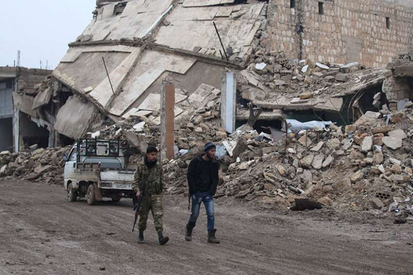 Rebel fighters walk near destroyed buildings in 2016 in Aleppo, Syria. Cardinal Mario Zenari, Syria&#039;s apostolic nuncio, says Syria&#039;s current situation is a &quot;bloodbath.&quot;