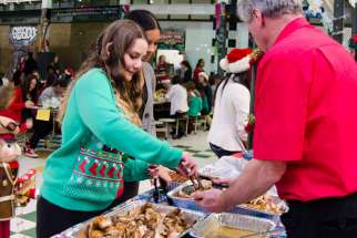 Vanessa Rasile serves food during Bishop Allen Academy’s annual Festive Dinner which brings those less fortunate in the community together to share a meal as one big family of friends.
