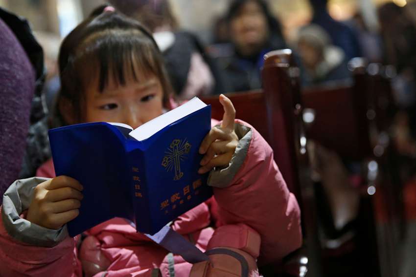 A girl reads a Bible during Mass in the state-approved Xuanwumen Catholic Church in Bejing, China, Dec. 4, 2016.
