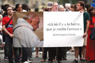 People hold a banner with a picture of French Fr. Jacques Hamel after a July 27, 2016, Mass at the Notre Dame Cathedral in Paris. The banner reads, “Where there is hatred, let me sow love.” On March 9, a French court sentenced four men in connection with the priest’s murder.