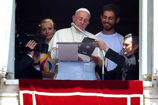 Pope Francis is flanked by two Polish youths as he uses a tablet to officially open online registration for World Youth Day 2016 in Poland. 