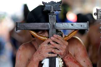 A penitent kisses a crucifix as he takes part in a Good Friday service in Manila, Philippines, March 25, 2016. Amid continuing concerns about the spread of the coronavirus, Catholics in the Philippines have been asked not to kiss or touch the cross when they venerate it on Good Friday, which this year is April 10.