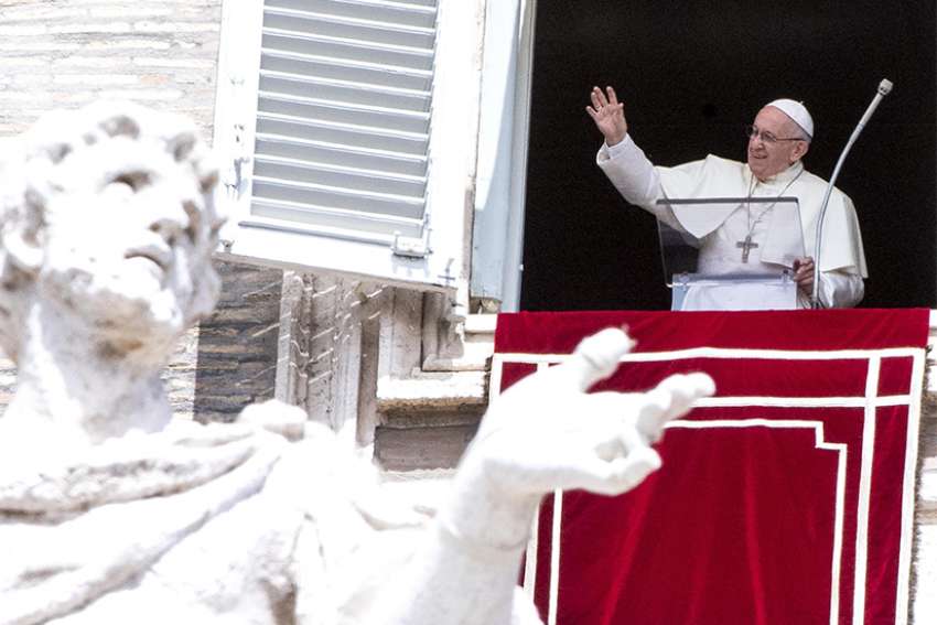 Pope Francis waves as he leads the Angelus from the window of his studio overlooking St. Peter&#039;s Square at the Vatican Aug. 15, the feast of the Assumption. 