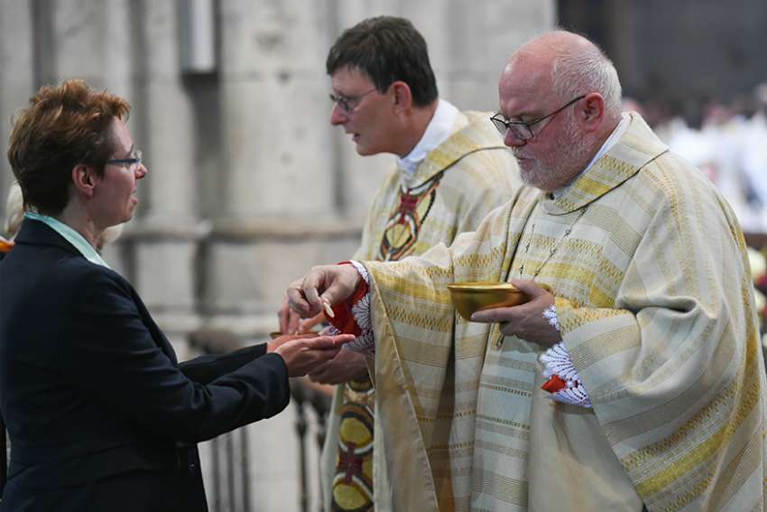 Cardinal Rainer Maria Woelki of Cologne, Germany, and Cardinal Reinhard Marx of Munich and Freising distribute Communion during Cardinal Woelki&#039;s installation Mass at the cathedral in Cologne Sept. 20, 2014.