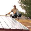 Luc Lafond fastens the metal roofing onto the cabin he and a group of volunteers built last November at St. Mary of Egypt Refuge.