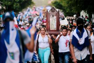 A woman and man carry a statue of Mary during a march in support of the Catholic Church July 28 in Managua, Nicaragua. The government is accusing Catholic bishops of siding with the opposition and encouraging protests. 