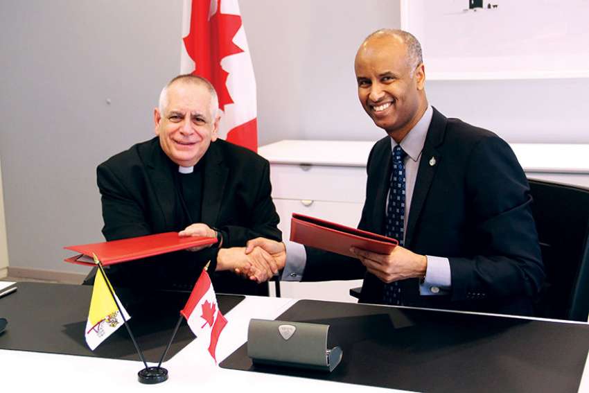 ICMC general secretary Msgr. Bob Vitillo and Canada’s Immigration Minister Ahmed Hussen shake hands after renewing a commitment by the Canadian government to help fund the Catholic migration agency. 