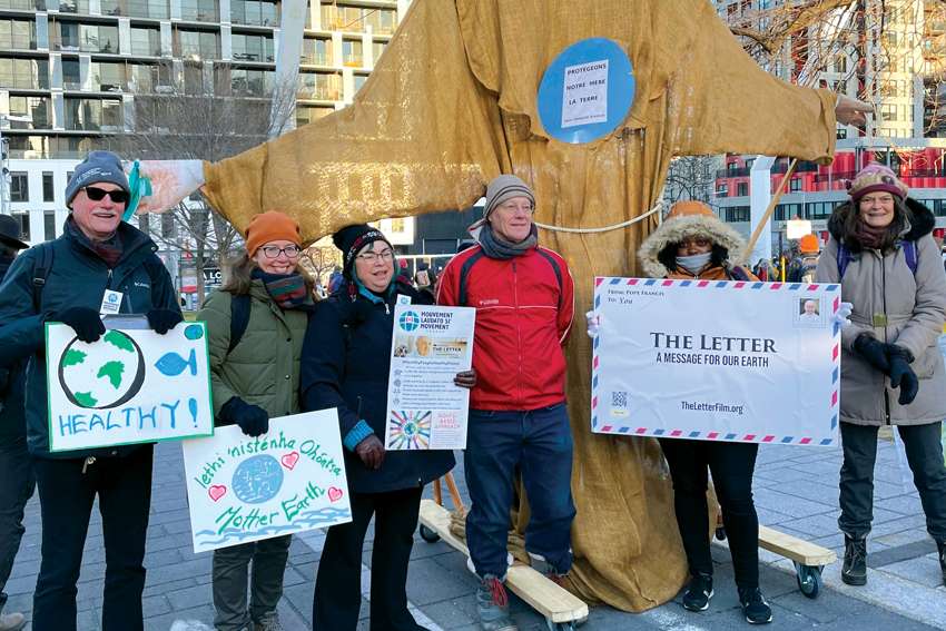Members of Catholic faith communities (Le Centre Oblat: A Voice for Justice, Sisters of St. Martha, the Laudato Si’ Movement and the Montréal archdiocese pause during the COP15 March for Biodiversity on Dec. 10 in Montreal with a puppet of St. Francis of Assisi.