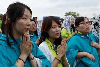 Young women pray as Pope Francis celebrates the closing Mass of the sixth Asian Youth Day at Haemi Castle in Haemi, South Korea, 2014.