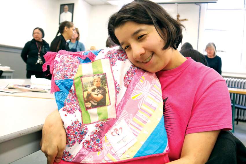 Gillian cuddles up to a blanket featuring a photo of her father, who passed away seven years ago, at a unique program for low-income or marginalized women grieving the loss of a loved one