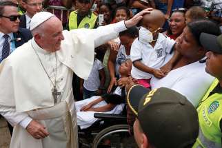 Pope Francis greets a sick child near the Talitha Qum homeless shelter in Cartagena, Colombia, Sept. 10.