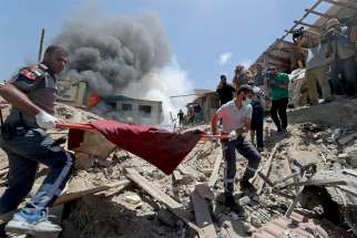 Palestinians evacuate a body from the site of Israeli strikes in Gaza City May 17, 2021.