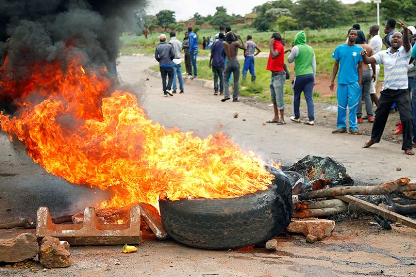 Protesters stand behind a burning barricade during protests over steep fuel price hikes Jan. 15 in Harare, Zimbabwe. 