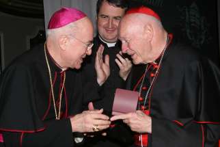 Archbishop Carlo Maria Vigano, then nuncio to the United States, congratulates then-Cardinal Theodore E. McCarrick of Washington at a gala dinner sponsored by the Pontifical Missions Societies in New York in May 2012. The archbishop has since said Cardinal McCarrick already was under sanctions at that time, including being banned from traveling and giving lectures. Oblate Father Andrew Small, center, director of the societies, said Archbishop Vigano never tried to dissuade him from honoring the cardinal at the gala. 