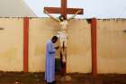 Father Paul Obayi prays in front of the crucifix at St. Mary&#039;s Cathedral in Enugu, Nigeria, Sept. 30, 2021. Catholic churches in Sokoto, Nigeria, suspended Masses May 15, 2022, after the government imposed a curfew to quell protests after arrests in the mob death of a college student.
