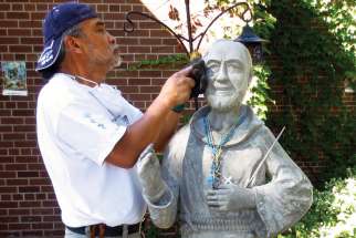 Sculptor and Knights of Columbus member Ignacio Mogado restores a statue of St. Padre Pio at St. Patrick’s Parish in Markham, Ont.