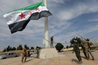 Turkish-backed Syrian rebel fighters raise the Syrian opposition flag at the border town of Tel Abyad, Syria, Oct. 14, 2019.
