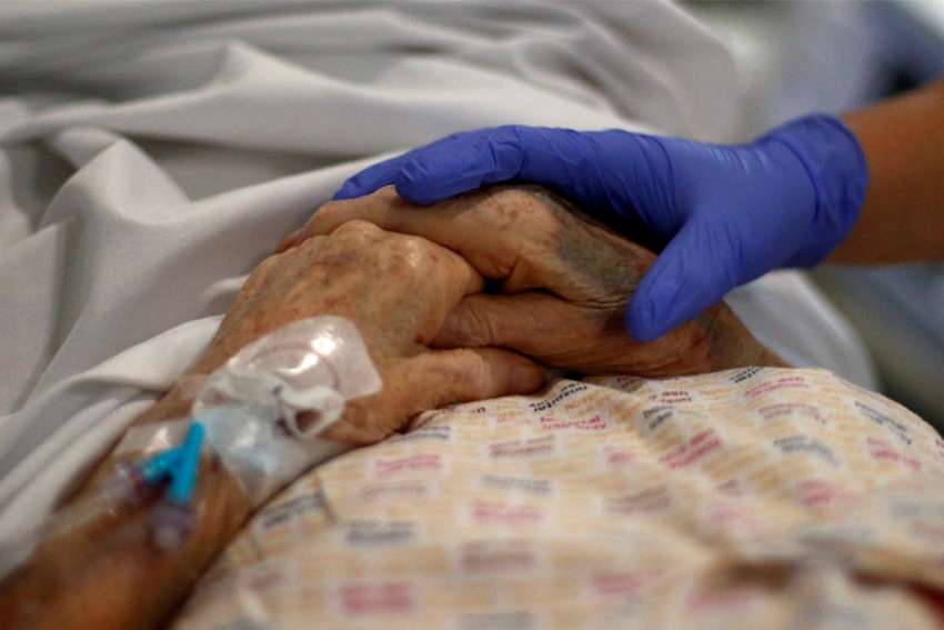 A health care worker comforts an eldery patient at a hospital in Blackburn, England, May 14, 2020, during the COVID-19 pandemic.