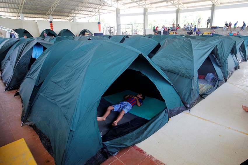 A child sleeps in a tent April 4, 2017, at a shelter for people left homeless after mudslides in Mocoa, Colombia. Caritas Colombia is working with international and national agencies to assess needs and generate a plan for the thousands of families left homeless.