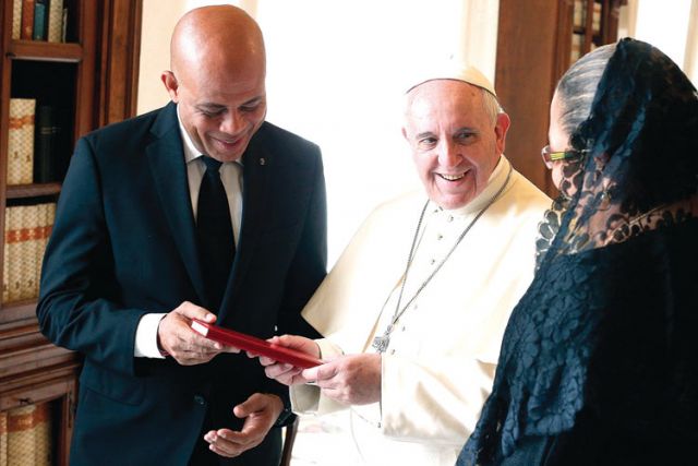 Pope Francis presents a book to Haiti’s President Michel Martelly, accompanied by his wife, Sophia, during a private audience at the Vatican Feb. 24.