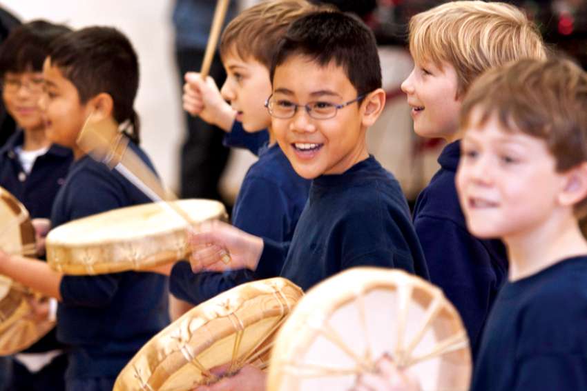 Students learning to play traditional drums at Brebeuf College School.
