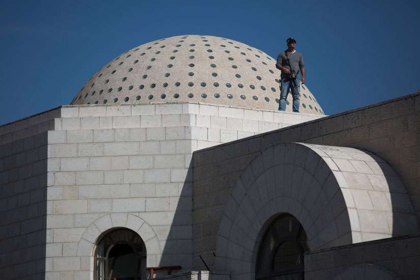 Police stand guard on the roof of a Jerusalem synagogue involved in a fatal attack Nov. 18. Two Palestinians are said to have killed four people with a meat cleaver and a knife before being shot dead by police, the deadliest such incident in six years in the holy city amid a surge in religious conflict.
