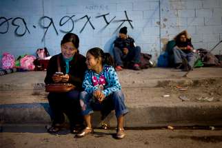  A mother and daughter wait outside a camp at a sports facility in Tijuana, Mexico, set up to for people arriving Nov. 15 in a caravan of Central American migrants at the U.S.-Mexico border. The shelter opened the previous night and had more than 750 people, but dozens more lined up outside waiting to enter. 