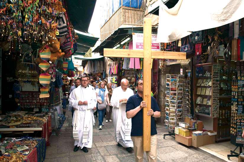 Catholic pilgrims walk past shops selling souvenirs on Via Dolorosa in Jerusalem’s Old City. 