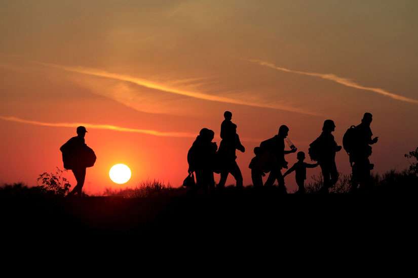 Migrants walk along at sunset after crossing into Hungary from the border with Serbia near Roszke, Hungary, Aug. 29. 