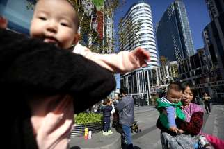 Women carry their babies in a shopping district in Beijing, China, in this Oct. 30, 2015, file photo.