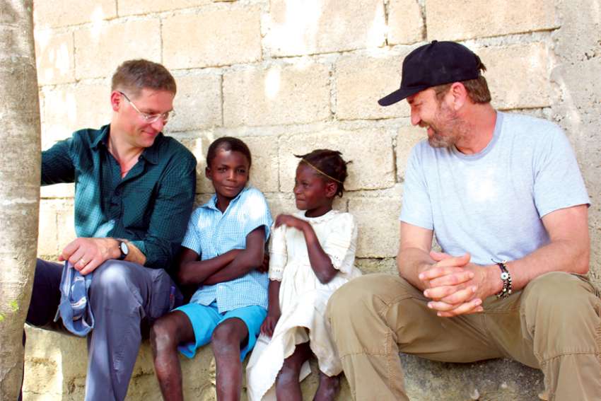 Mary’s Meals founder Magnus MacFarlane-Barrow, left, is joined by actor Gerard Butler, right, with some of the children Mary’s Meals supports through its program to alleviate poverty in 19 nations around the world.