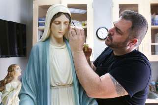 Artist Lou McClung paints a statue of Mary in his studio at the Museum of Divine Statues in Lakewood, Ohio, July 18. He has restored dozens of statues, many from closed churches in the Diocese of Cleveland that are now displayed in the museum he operates.