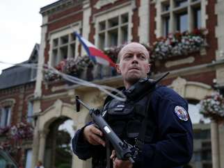 A policeman secures a position in front of the city hall after two assailants took five people hostage in the church at Saint-Etienne-du-Rouvray near Rouen in Normandy, France, July 26, 2016. The attackers killed a priest and seriously wounded another hostage before being shot dead by police.