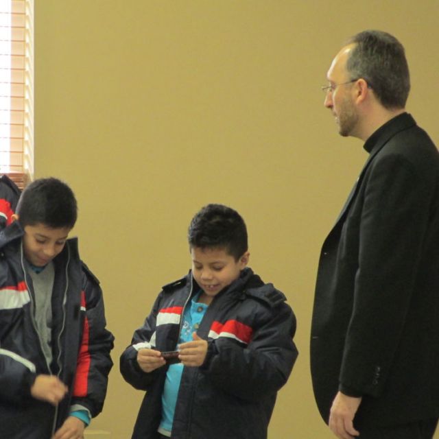Kids try on winter coats from the Knights of Columbus’ Coats for Kids program in the presence of Fr. Miguel Segura Blay, pastor of Toronto’s Our Lady of Guadalupe parish.