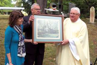 At the anniversary Mass held Sept. 15 at St. Mary’s Cemetery, Fr. Cornelius (Con) O’Mahony, pastor at St. Andrew’s, is presented with a limited edition historical print of the church done by Oakville artist Michael Hitchcox. Kevin Gleeson and Terry Murphy make the presentation.