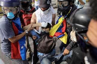 A group of demonstrators tries to help a man after he was shot by a Venezuelan military police sergeant June 22. On July 16, a armed civilians who support the Venezuela government opened fired against a large crowd. One person died from gunshot wounds and several others were injured.