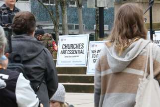 Protesters outside the B.C. Supreme Court with signs demanding church services be allowed.