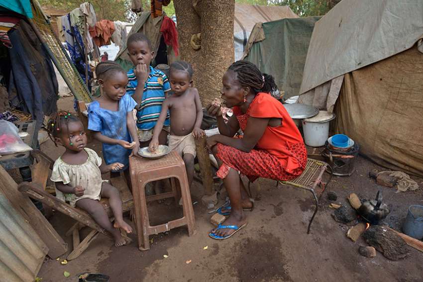 A mother and her children eat a meal at a camp for internally displaced persons on the grounds of St. Mary Catholic Cathedral April 24 in Wau, South Sudan. Drought and armed conflict have pushed tens of thousands of Wau-area residents out of their homes, away from their farms and unable to adequately feed themselves.
