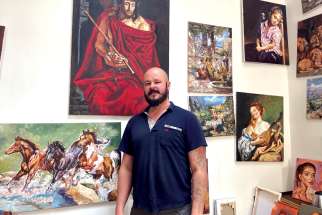 Adam Piekarski stands in front of his paintings in his studio at Palazzo Migliori, the Vatican’s homeless shelter, Dec. 1. Piekarski, a homeless man from Poland currently living in Rome, was commissioned to paint images for the Vatican’s 2021 Christmas stamps.