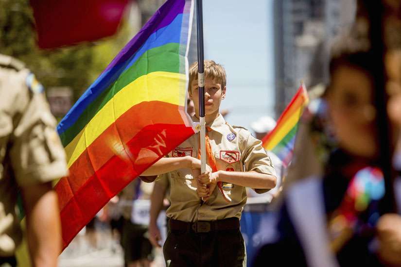 In this June 29, 2014 file photo, a Boy Scout carries a rainbow flag during the San Francisco Gay Pride Festival in California. Boy Scouts of America lifted a ban on openly gay troop leaders today.