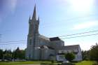 Église Sainte-Marie in Church Point, N.S., features a 56-metre (185-foot) steeple that houses three bronze bells. Right, the church under construction in 1904.
