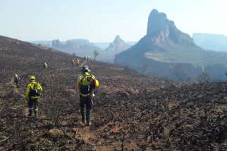 Firefighters near Robore, Bolivia, walk where wildfires have destroyed the forest Aug. 19, 2019.